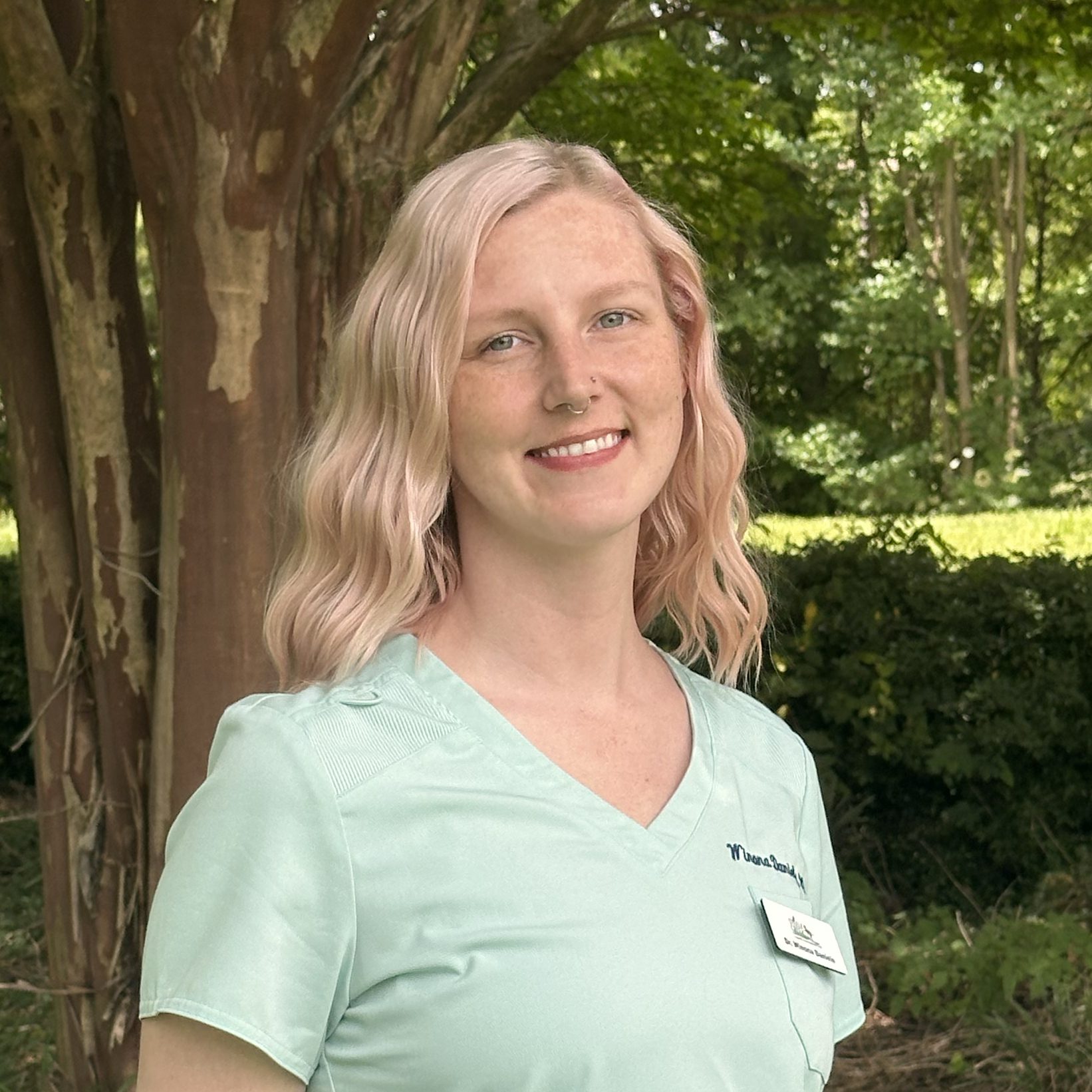 female with blonde wavy hair wearing a light blue vtech short sleeved top