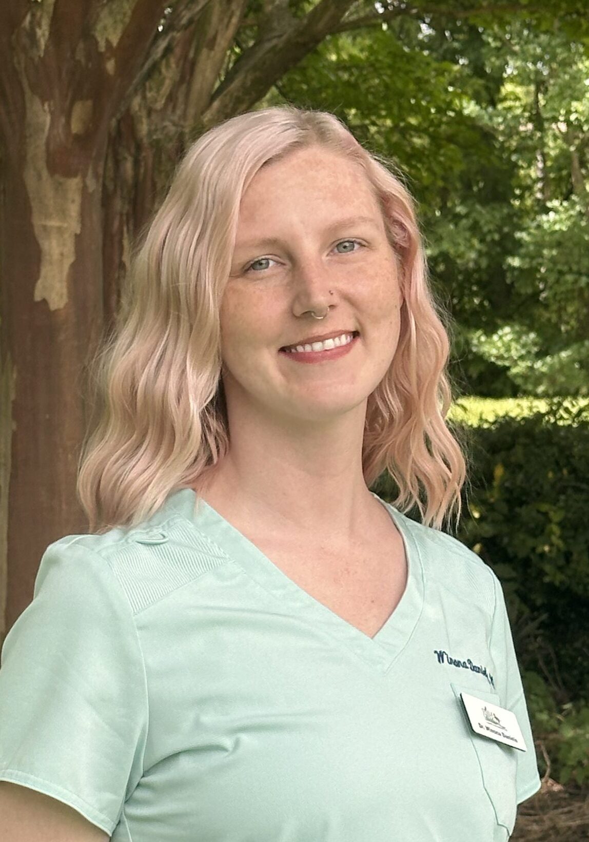 female with blonde wavy hair wearing a light blue vtech short sleeved top
